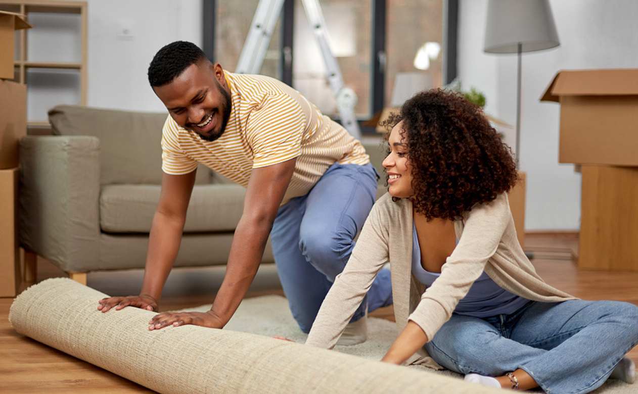 young couple rolls out area rug in home renovation